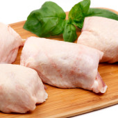 Fresh chicken thighs on a wooden chopping board - shallow depth of field - white background